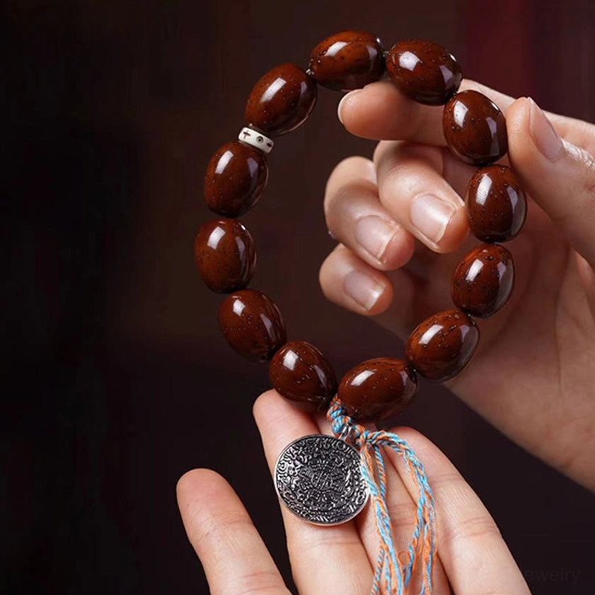 Purple gold rat wealth bracelet held in two hands showing barrel beads and silver OM pendant