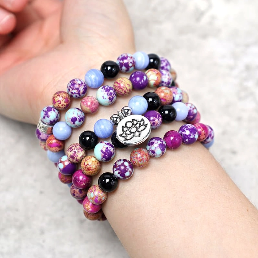 Purple Miano stone lotus mala worn on wrist showing stacked bracelet style with silver lotus charm on light skin tone