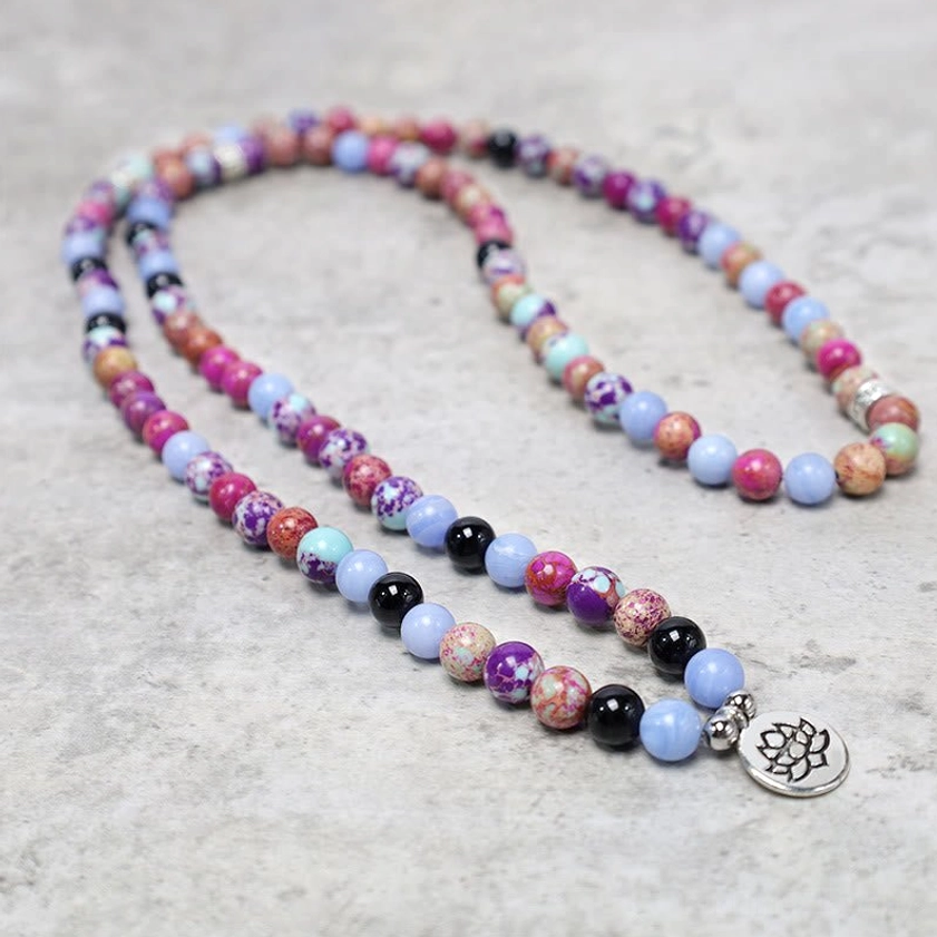 Long purple Miano stone lotus mala necklace with hanging silver lotus charm showing uniform bead spacing from overhead view