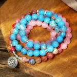 Purple and pink Miano mala beads with lotus charm laid flat on wooden board - authentic 108 bead Buddhist bracelet for meditation