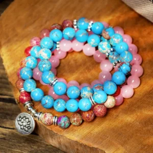 Purple and pink Miano mala beads with lotus charm laid flat on wooden board - authentic 108 bead Buddhist bracelet for meditation