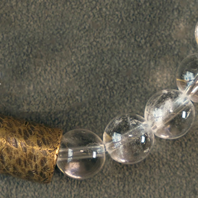 Macro close-up of multi-crystal bracelet showing bead connections and textured bronze spacer detail