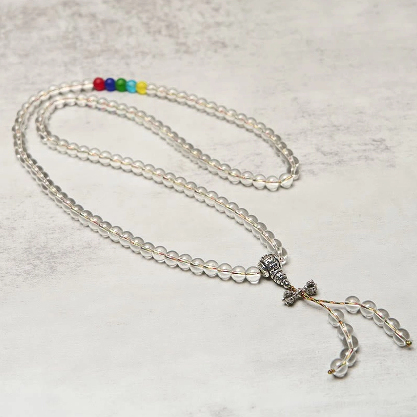 Long quartz mala necklace with vajra tassel pendant - flat lay showing smooth clear crystal round beads and colorful spiritual beads