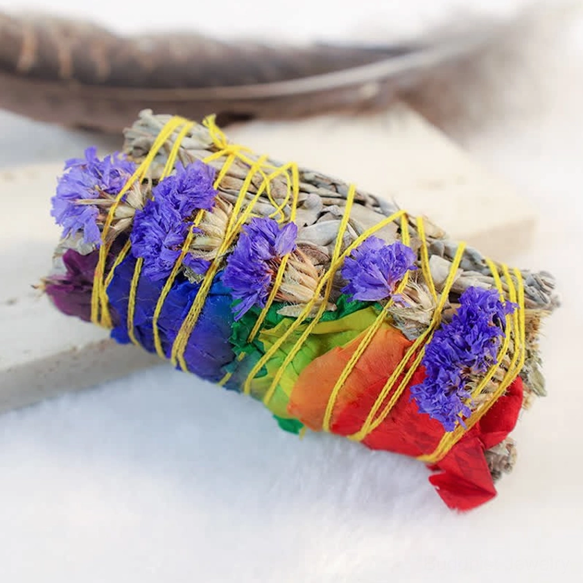 Close-up of purple and rainbow colored dried flower smudge stick with yellow cotton binding