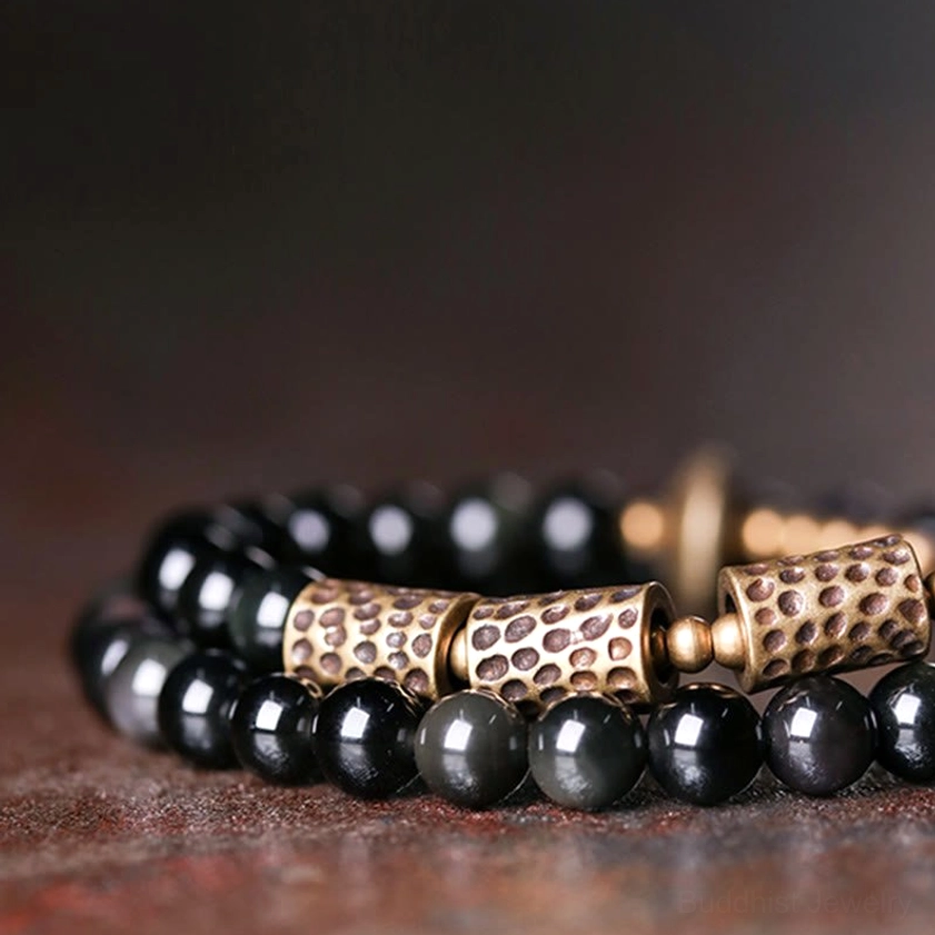 Front flat lay close-up of rainbow obsidian copper bracelet showing clear bead texture, bronze hammered accents, and glossy obsidian beads with rainbow glow