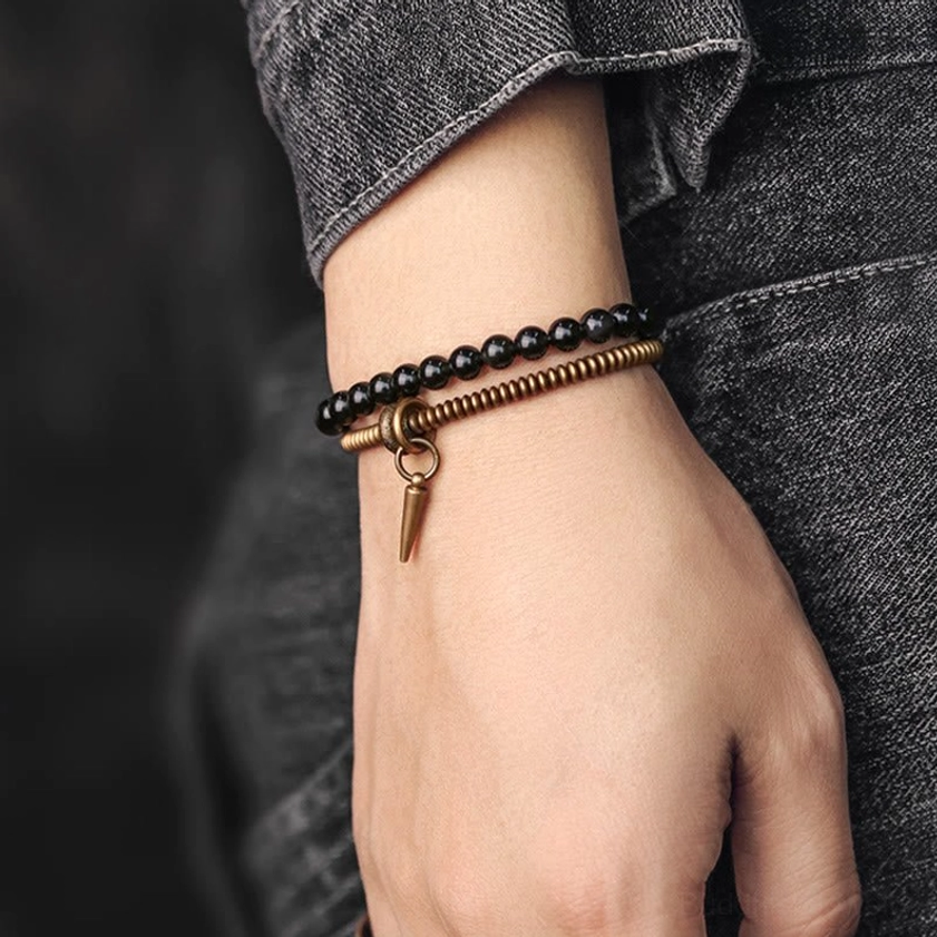 Two-style rainbow obsidian bracelet comparison with black bead strand and bronze coil strand with spike pendant