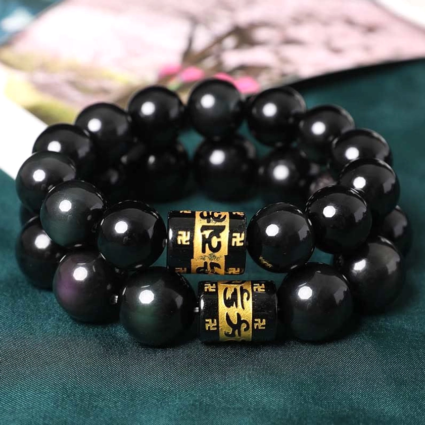Stacked rainbow obsidian Buddhist bracelets featuring glossy black beads and golden spacer beads - flat lay
