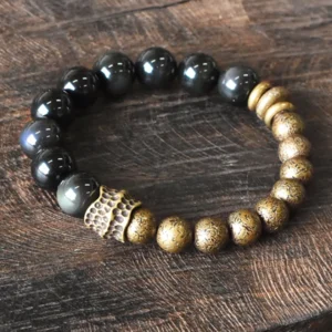 Rainbow obsidian and antique copper beaded bracelet with carved metal spacers, oblique overhead view on wood surface