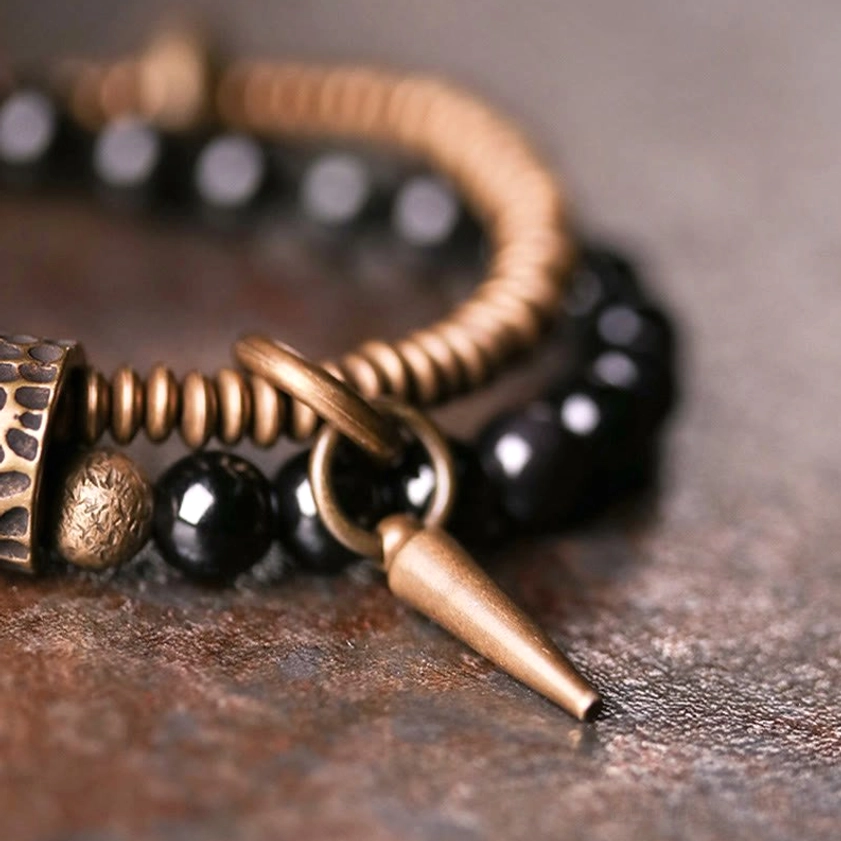 Double layer rainbow obsidian bracelet with spike charm and bronze accents, vintage wooden background