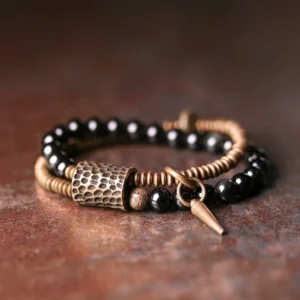 Rainbow obsidian double layer bracelet with copper hardware and spike charm, flat lay view showcasing antique bronze accents