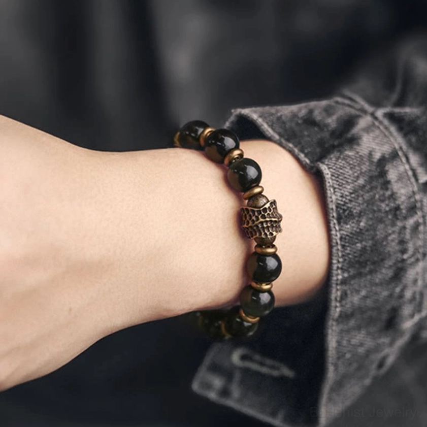 Double-strand rainbow obsidian bracelet with intricate carved metal charm, layered beaded design worn on wrist for enhanced spiritual energy