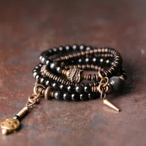 Rainbow Obsidian Ebony Wood Copper multilayer Buddhist bracelet set displayed overhead on vintage desktop with bronze hardware and tassel pendants