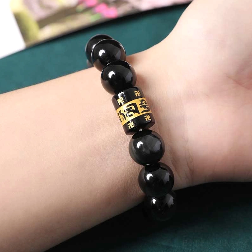 Rainbow obsidian Buddhist bracelet worn on wrist showing golden mantra bead close-up - side view