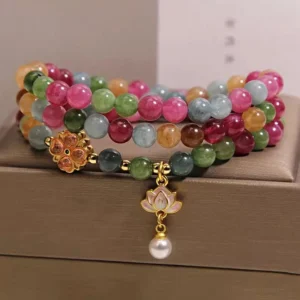 Rainbow tourmaline triple wrap lotus bracelet with gold flower clasp and pearl pendant on jewelry box