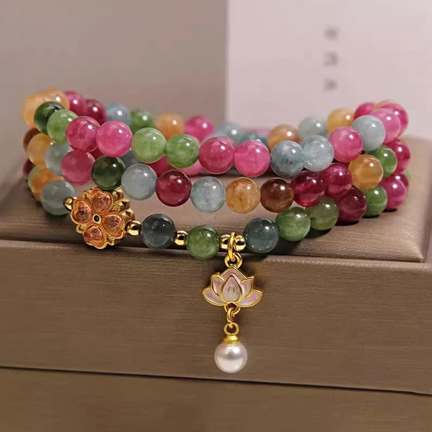 Rainbow tourmaline triple wrap lotus bracelet with gold flower clasp and pearl pendant on jewelry box