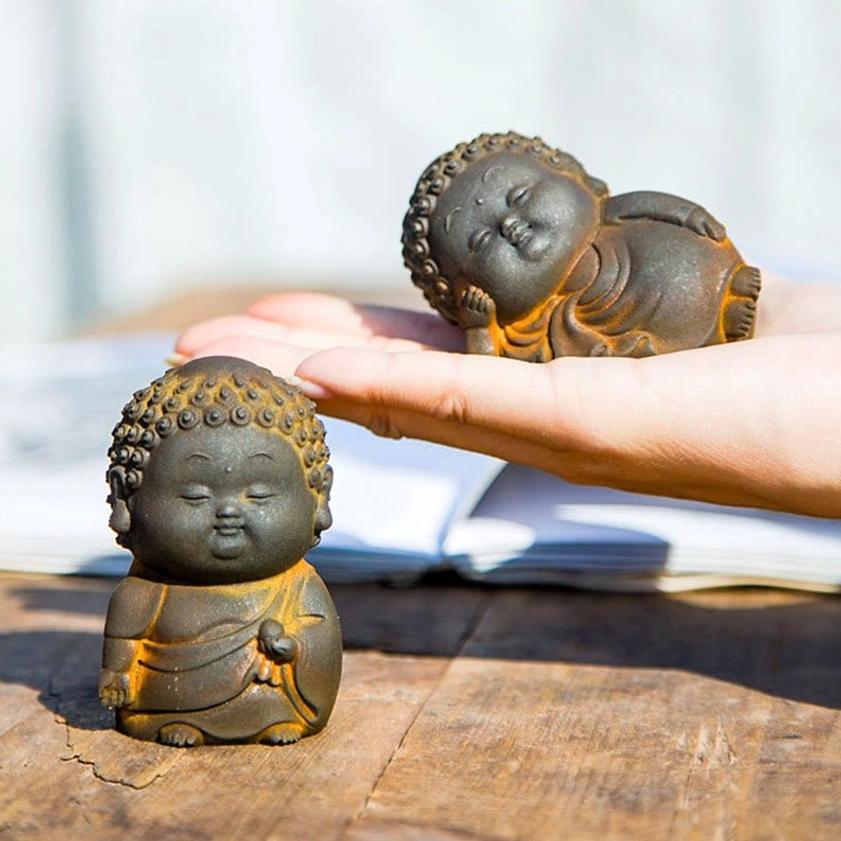 Reclining Buddha figurine held in hand showing textured matte rough rustic painted surface and natural patina