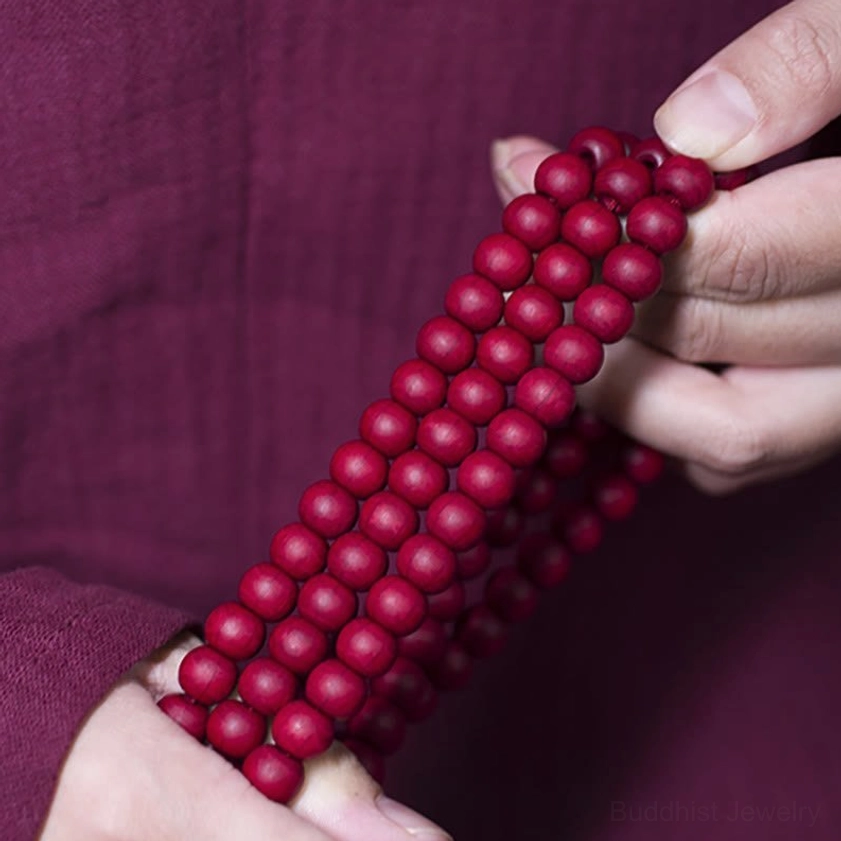 Close-up of bundled red Abelia wood mala beads showing uniform round bead craftsmanship and natural wood texture