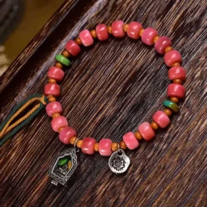 Red agate and camel bone Buddhist bracelet with copper accents overhead view on wooden surface