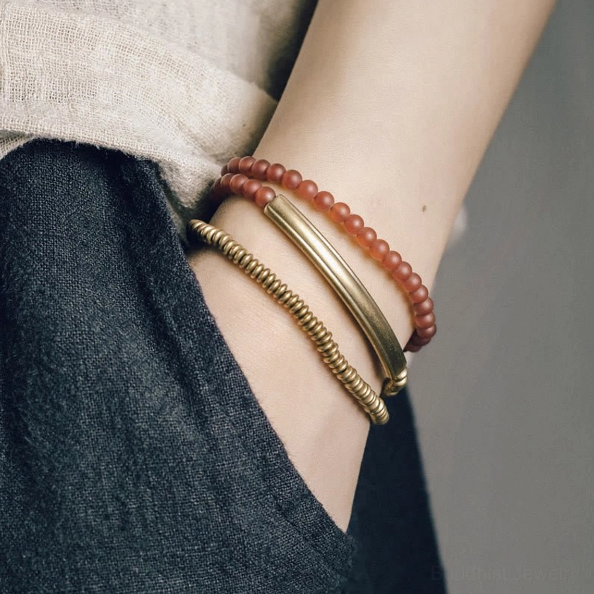 Slim red agate copper Buddhist bracelet stacked wrap design worn on wrist with linen clothing showing side profile minimalist styling
