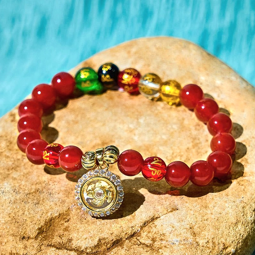 Red agate cyclone charm bracelet with rotatable gold pendant and mixed accent beads on stone
