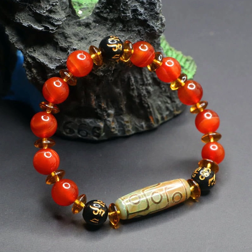 Buddhist red agate dzi bead bracelet full loop displayed on stone - complete wearable view