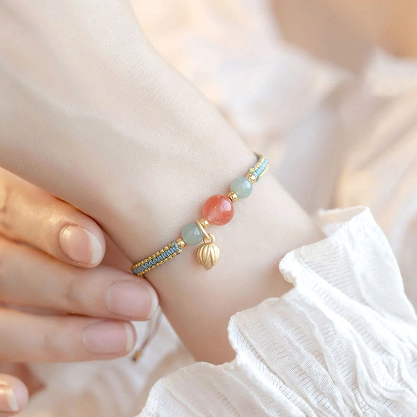 Red agate lotus bracelet worn on wrist with white ruffled cuff feminine styling