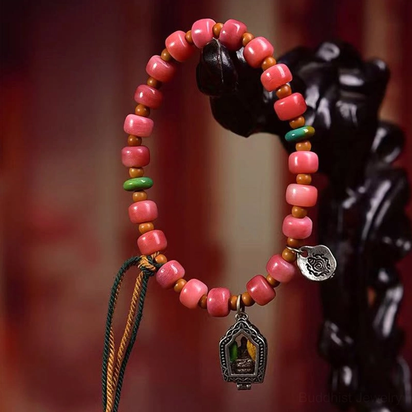 Red agate luck bracelet with braided tassel close-up showing beads and metal shrine charm