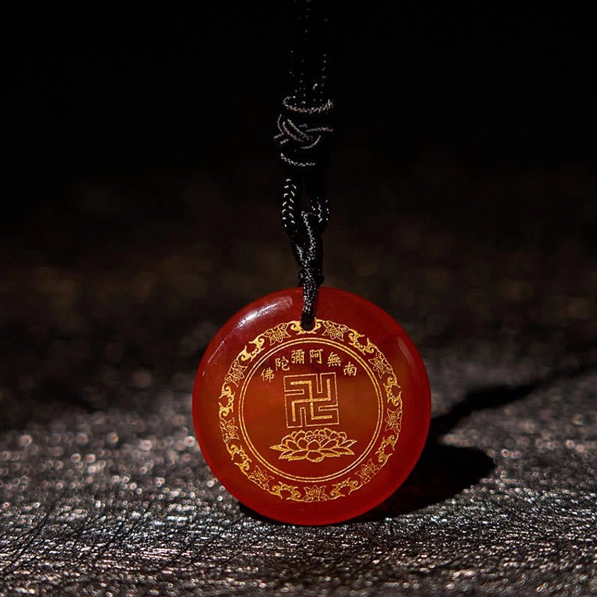 Red agate Buddhist pendant with braided cord oblique side view on textured background