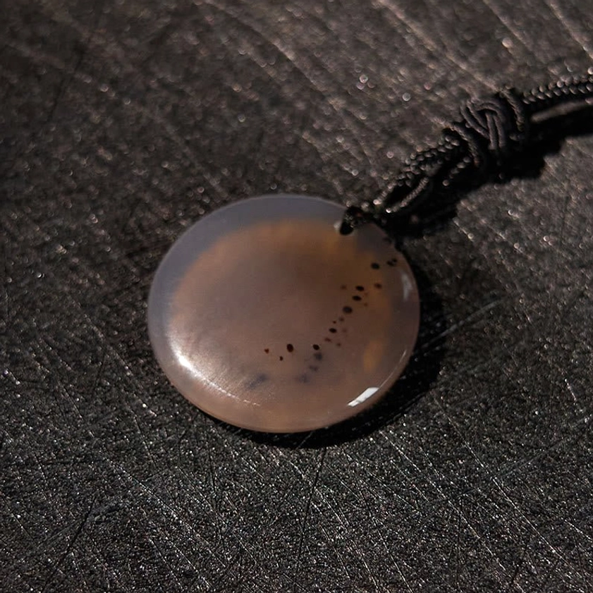 Red agate Buddhist pendant overhead flat lay showing swastika pattern detail