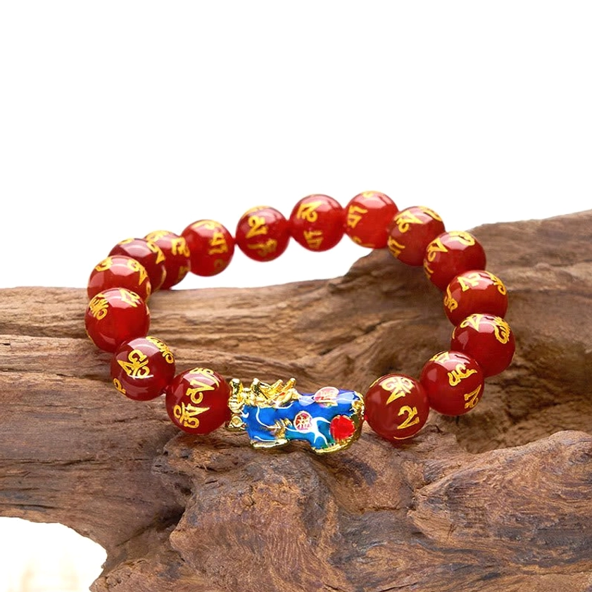 Oblique shot of red agate Pixiu Om Mani Padme Hum bracelet on wooden log surface, glossy polished beads with gold text details and color-changing Pixiu charm