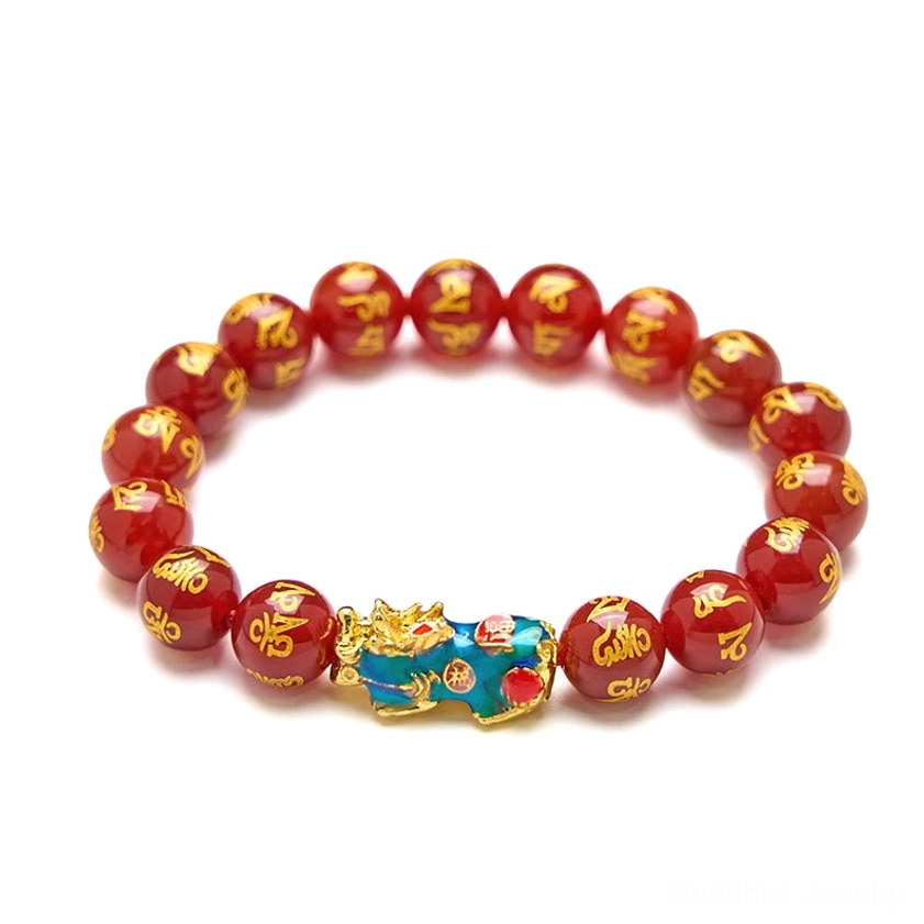 Overhead product shot of red agate Pixiu bracelet on white background, uniform polished red beads with gold text engravings and prominent blue-gold Pixiu ornament