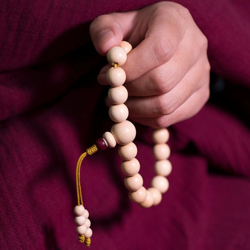 Red bead Abelia Biflora wood Buddhist prayer mala bracelet with golden tassel in hand-held view