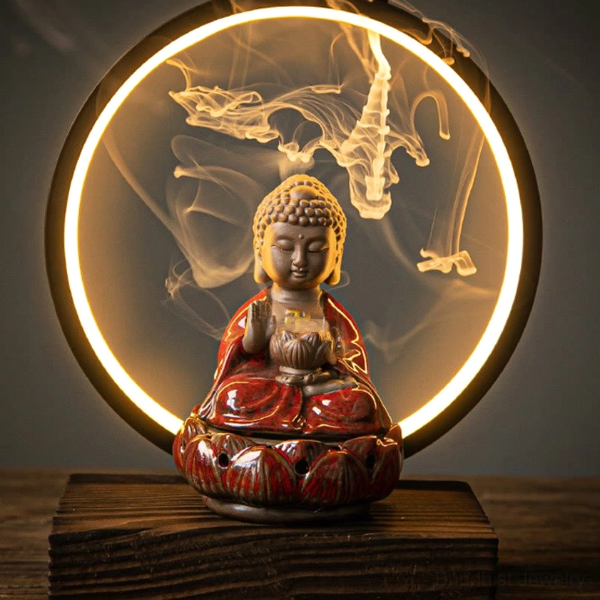 Red glazed Buddhist ceramic backflow incense burner with LED light on wooden table displaying cascading smoke effect