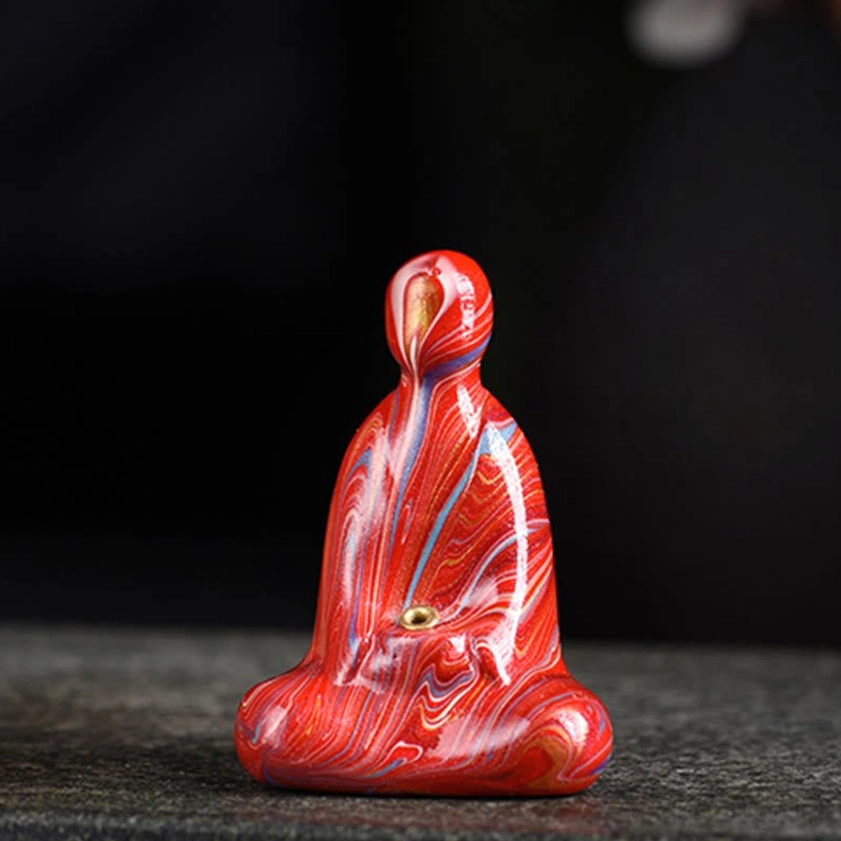 Single red marbled ebony wood Buddha incense holder on dark stone desktop background