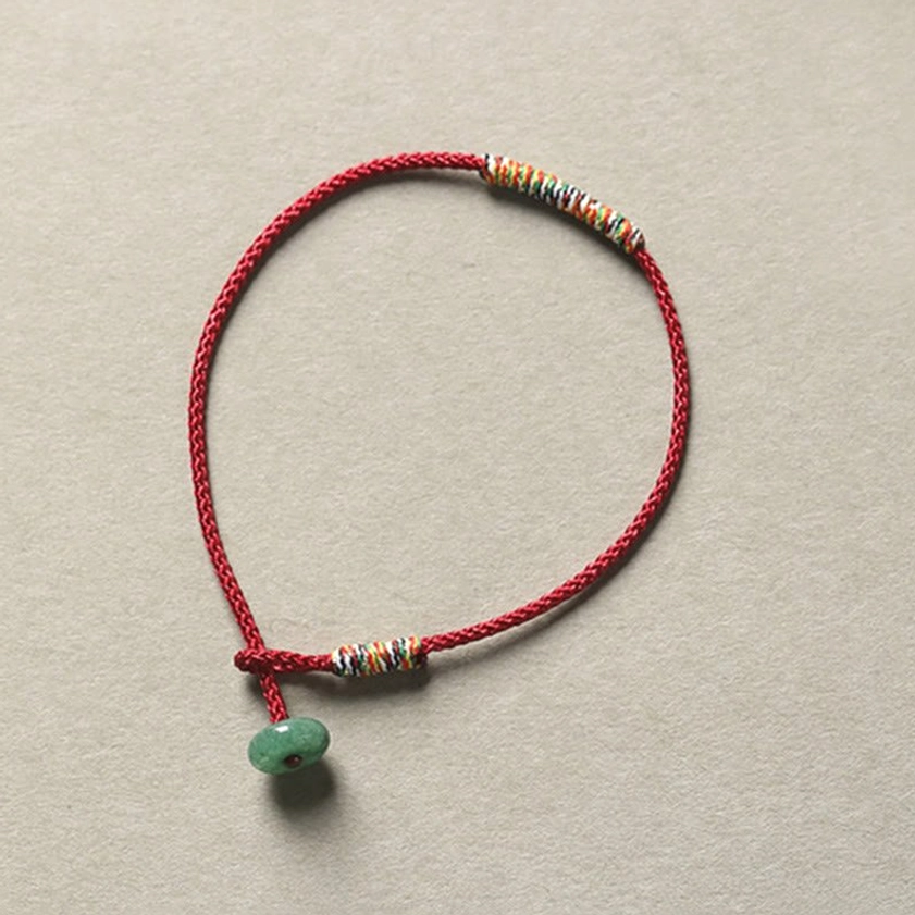 Red braided Buddhist string bracelet with green aventurine pendant and woven trim, spiritual luck and protection bracelet