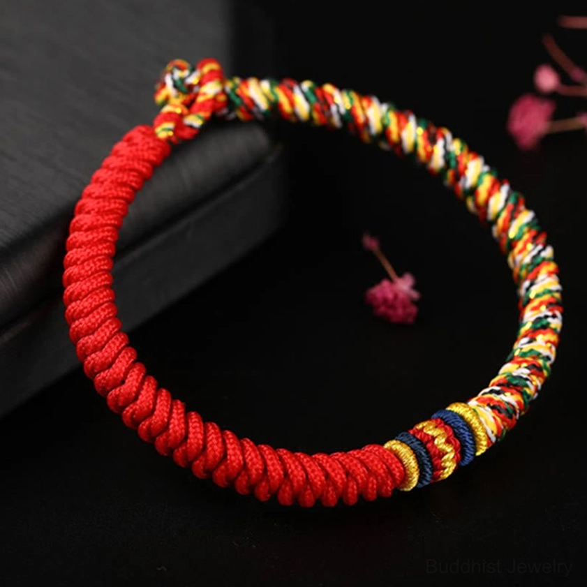 Red handmade Buddhist King Kong Knot bracelet flat lay view with multicolored decorative knots and detailed braiding pattern