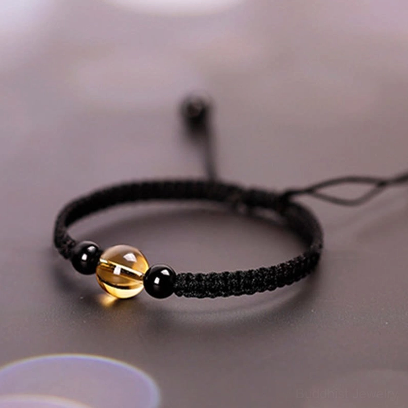 Buddhist red string bracelet with citrine and black obsidian beads showing spiritual knot work