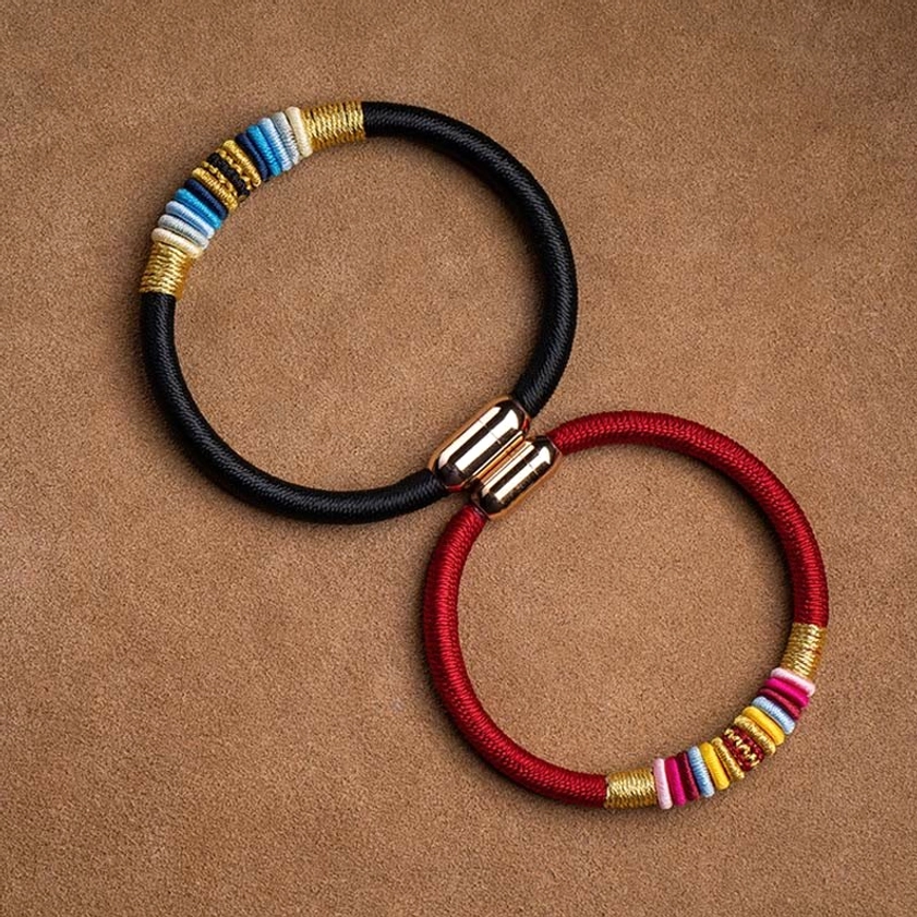 Red Buddhist string bracelet with colorful decorative elements and gold clasp