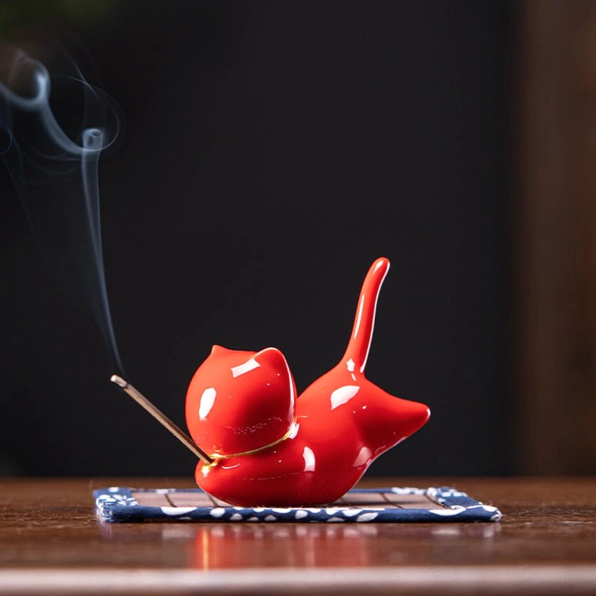 Red cat ceramic incense burner with gold collar accent, showing incense stick placement and smoke, spiritual meditation tool for home altar
