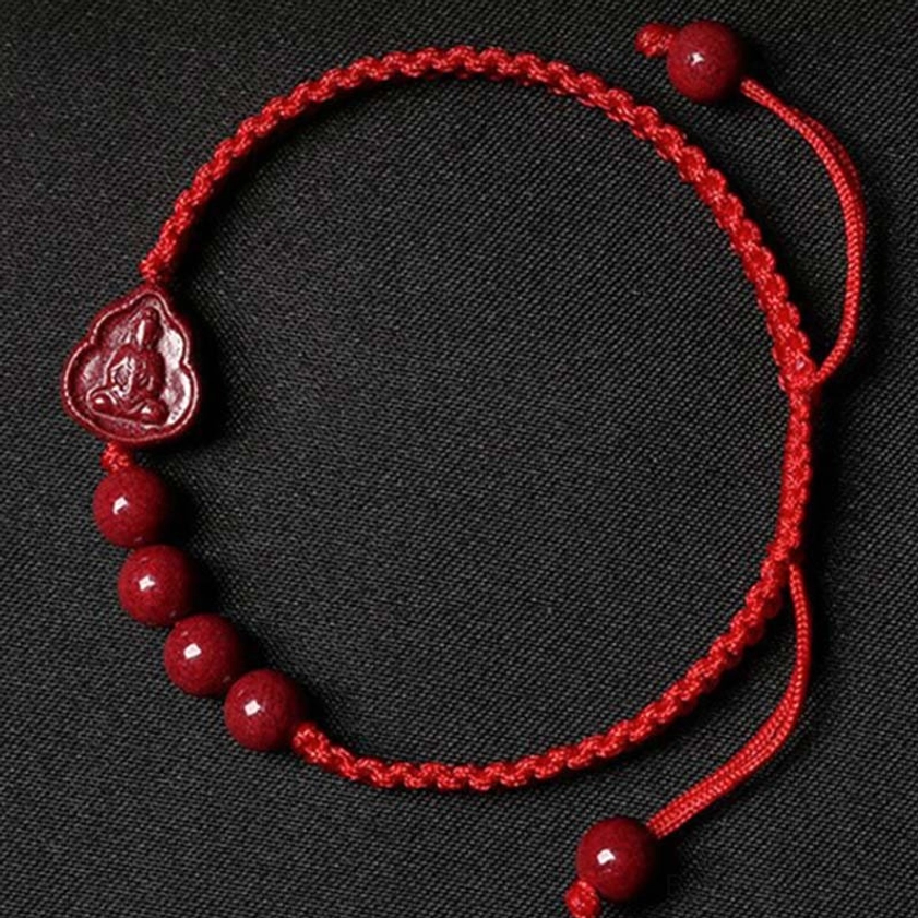 Red string cinnabar Buddha bracelet flat lay top-down view with Buddha pendant and adjustable beads