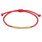 Red braided Buddhist protection bracelet with polished copper beads and adjustable pull-knot closure, front flat lay view