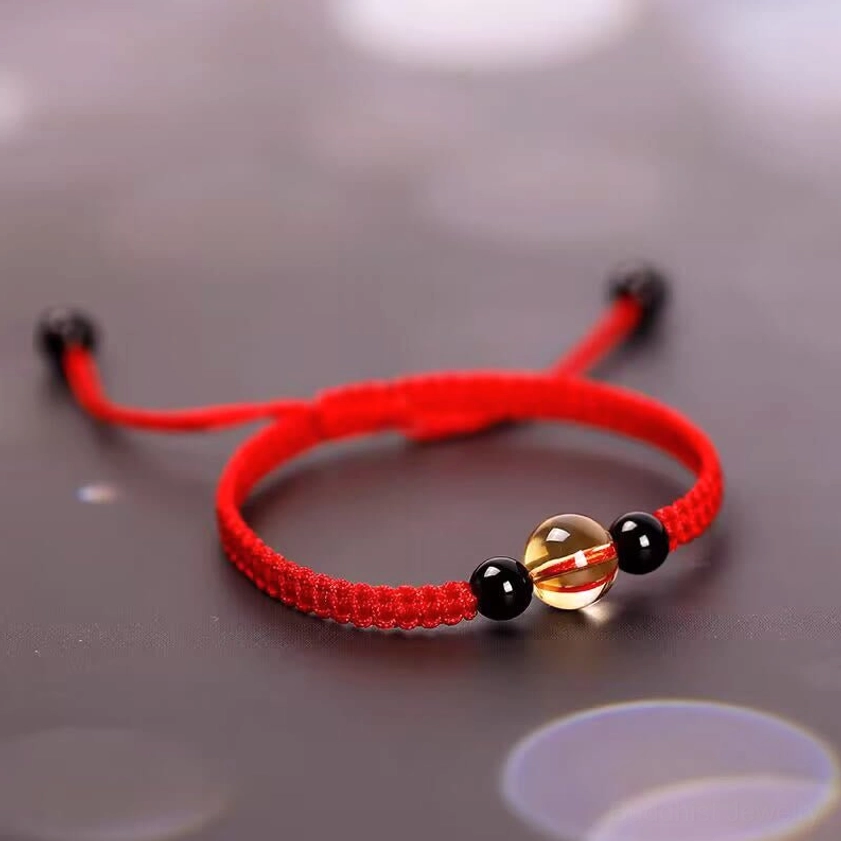 Red beaded bracelet showing adjustable pull cord fastening system and polished stone accents