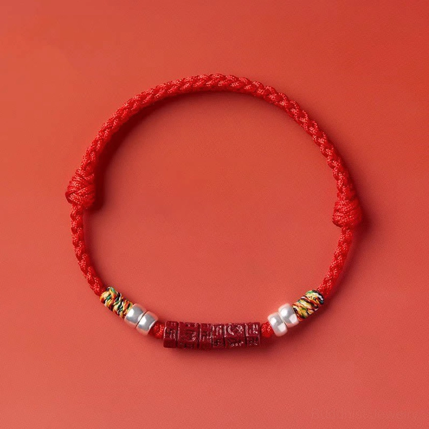 Red cord bracelet with cinnabar beads and silver components showing texture and natural material variations