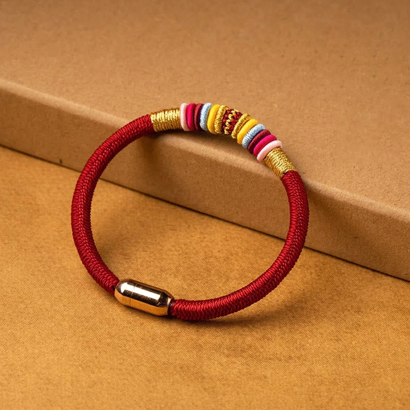 Red cord Buddhist bracelet with king kong knot design and decorative beads side angle view