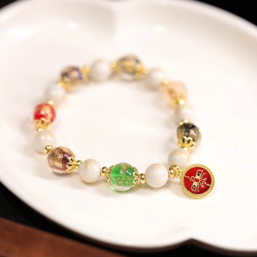 Red God of Wealth Buddhist charm bracelet with liuli glass beads and incense ash porcelain, displayed on white porcelain plate