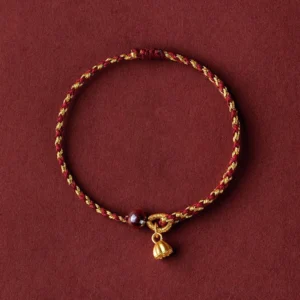 Red gold braided lotus bracelet with dark red bead and gold lotus charm pendant - flat lay view