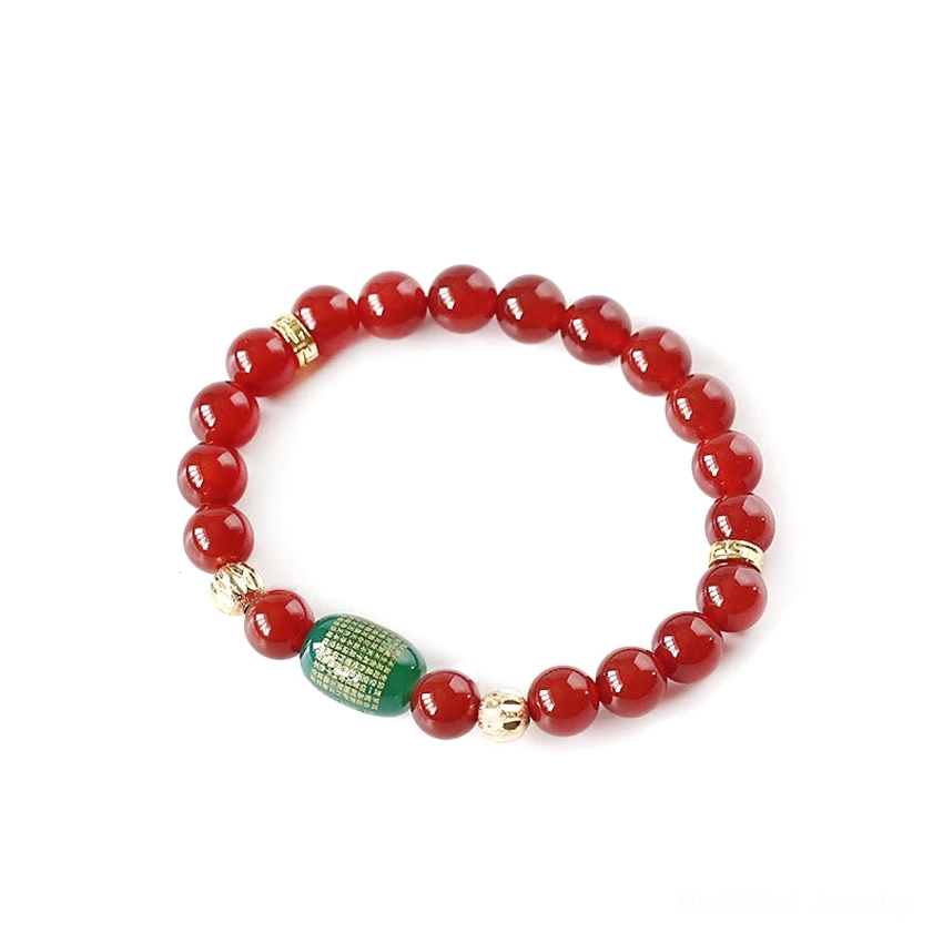 Red agate round beads with green engraved barrel bead and gold-plated copper spacers, white background flat lay
