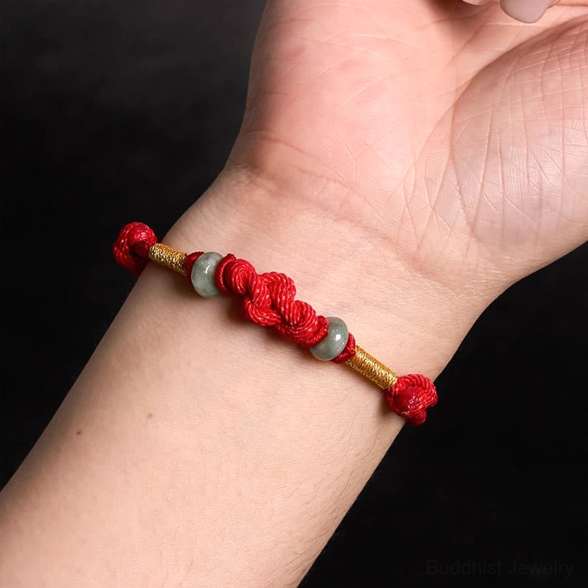 Red string jade bracelet being worn on wrist showing natural fit and classic knot bead layout against dark background