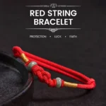 Red string jade fortune knot bracelet with gold twisted cord accent and light green jade bead, displayed on dark surface showing braided knot design