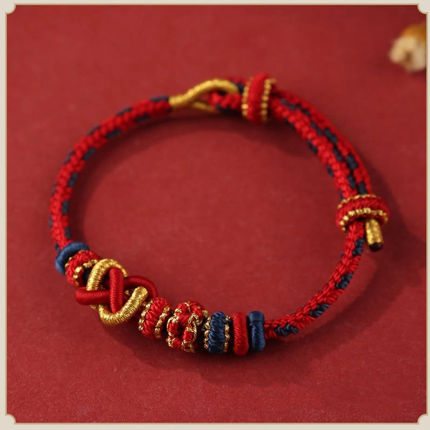 Red and gold peace knot Buddhist bracelet flat lay - handcrafted adjustable string design with protective spiritual symbolism